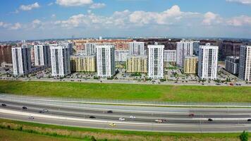 A bright bird's-eye view.Stock footage.Large high-rise buildings located in rows, next to the highway along which different cars move and a beautiful blue sky overhead. video
