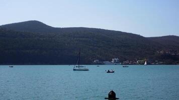 A beautiful bird's-eye view of the landscape. Action . A view of the blue ocean, mountains and green trees standing on them and you can see small sails that float near the shore. video