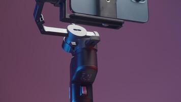 Stabilizer for the smartphone with three cameras isolated on a pink wall background. Action. New professional steadicam for shooting and a phone. video