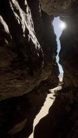 A narrow passage in a cave with sunlight coming through video