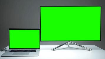 New TV models. Action.A small laptop that is comfortable to use and a large plasma TV with green screens. video