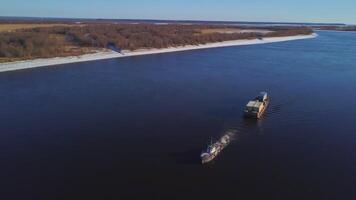 River tow pusher with barge. Clip. Top view of barge floating with cargo on river. River barge pusher picturesquely floats on background of horizon on sunny day video