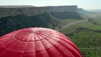 Top view of balloon at dawn with rock. Shot. Summer balloon festival at dawn. Balloons in green summer field with rock video