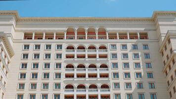 A huge beautiful hotel. Action.A huge building like a palace with large windows and white ornaments and a blue sky behind. video