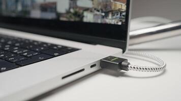 Closeup of USB flash drive inserted into port on the side of a laptop. Action. Part of laptop with a screen and movie. video