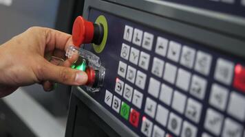 Operator is using the machine control panel which has an emergency stop button for safety measures video