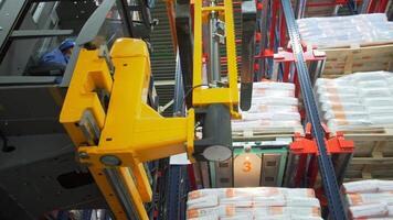 Russia Moscow - February 24, 2022. Warehouse worker driver in uniform moving cardboard boxes by forklift stacker loader. Creative. Forklift pallet with boxes in large modern warehouse. video