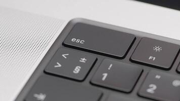 Part of the black keyboard in the frame. ACTION. Black keyboard in a silver laptop. Corner with buttons on the keyboard of a silver laptop video
