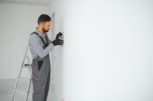 Serious male electrician installing power socket in the apartment and using screwdriver photo