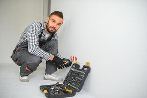 Serious male electrician installing power socket in the apartment and using screwdriver photo