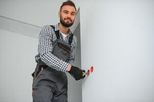 Electrician Builder at work, installation of sockets and switches. Professional in overalls with an electrician's tool. Against the background of the repair site photo