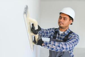 An Indian worker works in an empty apartment. A man in a uniform makes repairs inside the building photo