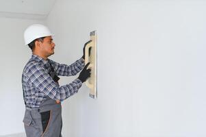 An Indian worker works in an empty apartment. A man in a uniform makes repairs inside the building photo