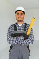 profession, construction and building - happy smiling indian worker or builder in helmet over grey background. photo