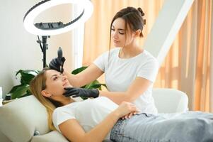 Process of creating permanent brow makeup with a machine at beauty salon photo