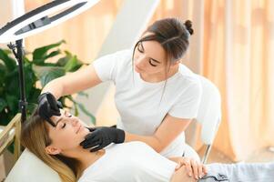 Process of creating permanent brow makeup with a machine at beauty salon photo