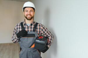 Portrait of a confident repairman with beard standing in empty apartment photo