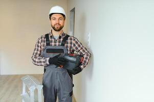 Portrait of a confident repairman with beard standing in empty apartment photo