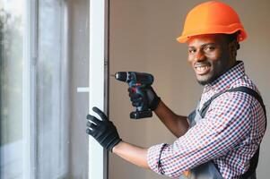 Close-up Of Young African Handyman In Uniform Installing Window photo