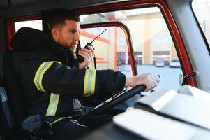 Side view of firefighter in protective uniform driving fire engine photo