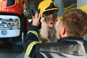 A fireman shows his work to his young son. A boy in a firefighter's helmet photo