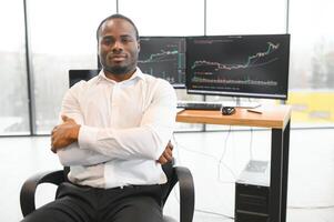 African American trader works at computer with displayed real-time stocks photo
