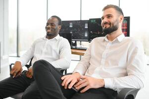 Two successful trader sitting in office, checking cryptocurrency information data on finance market graph, pointing on monitor photo