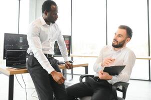 Two confident businessmen, financial analysts or investment advisers sitting at office desk photo