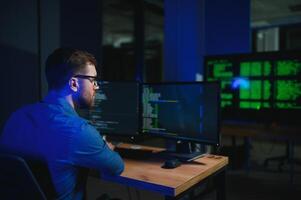 Male programmer working on desktop computer at white desk in office photo