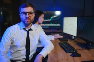 Team of stockbrokers are having a conversation in a dark office with display screens photo