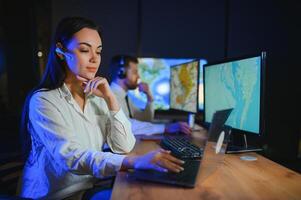 Center of dispatching maintenance. Portrait of cheerful woman and man working via headset microphone while sitting on navigation controller board photo