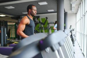 Sportive black man exercising on treadmill in fitness club photo