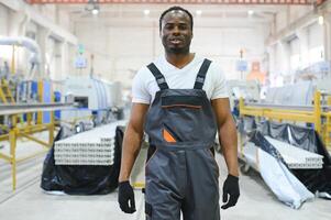 Portrait of African American male engineer in uniform and standing in industrial factory photo