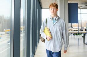 A young guy college student with a backpack is standing in the hall of the university photo