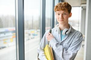 A young guy college student with a backpack is standing in the hall of the university photo