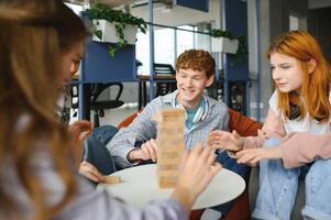 The company of young people plays a table game called jenga photo