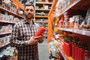 A man holds a fire extinguisher in his hand. A buyer in a hardware store selects a product photo