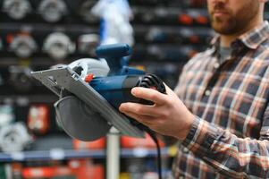 A man in a hardware store chooses a new orbital sander photo