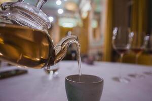 Close-Up of Glass Teapot Pouring Tea in Luxurious Upscale Setting photo