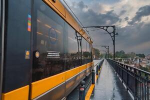 Yellow Metro Train on Dom Luis I Bridge in Porto on an Overcast Day photo