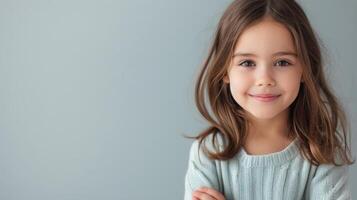 Young Girl Smiling With Arms Crossed Against Gray Background photo