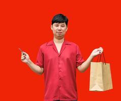 joyful Asian man carrying shopping bags and a credit card. on red background. Chinese New Year theme photo