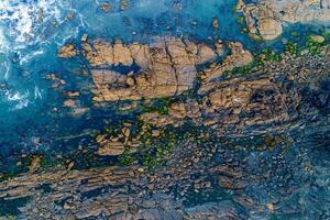 Aerial drone overhead view of the ocean rocky shore. aerial view of blue ocean waves splash on cliff. photo