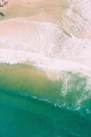 foam from the waves arriving at the shore of the beach aerial view from a drone photo