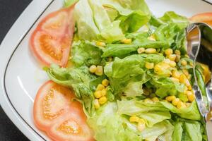 close-up view of a salad with lettuce, tomato, and sweet corn. Healthy diet food photo