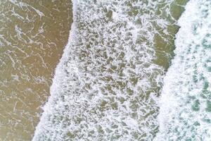 waves on the shore of a beach in the summer, aerial top view with drone photo