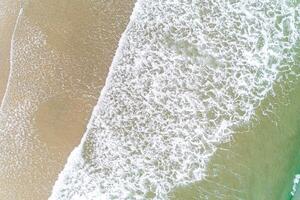 waves on the shore of a beach in the summer, aerial overhead view with drone photo