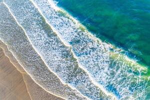 zenithal aerial view with drone of the waves of a beach at sunrise, background for summer concept photo