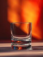 A clear empty glass positioned against a background of warm, glowing light reflections, creating a cozy and inviting atmosphere. photo