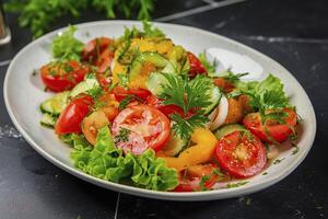 A white plate with a salad of tomatoes, cucumbers, and lettuce photo